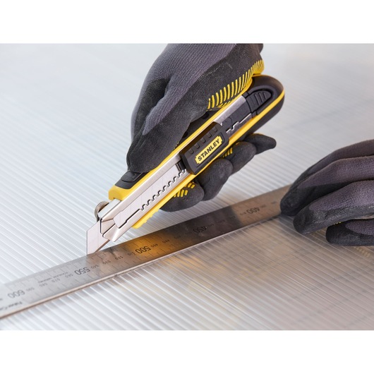 STANLEY 0-10-481 utility knife cutting along a metal ruler, close-up shot with gloved hands.