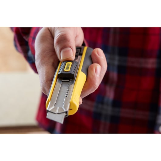 STANLEY 0-10-481 utility knife held in hand, yellow and black handle, close-up view.
