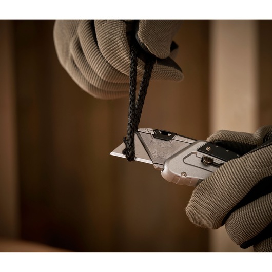 STANLEY 0-10-810 utility knife cutting black rope, close-up of gloved hands using silver knife.