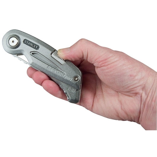 Photo of STANLEY 0-10-813 utility knife held in a hand, silver metal body, side view.