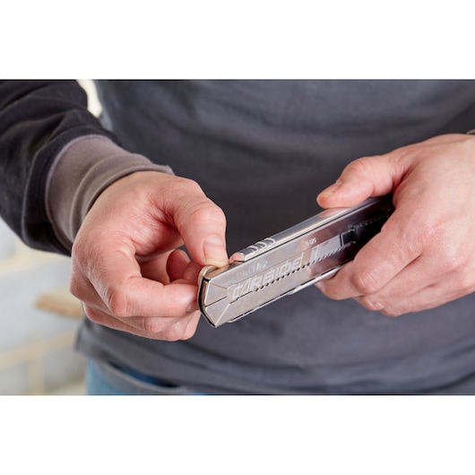 Photo of STANLEY 0-10-820 retractable utility knife being used, silver metal body visible in hand.