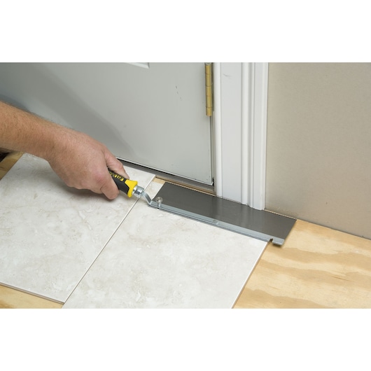 STANLEY 0-15-252 flooring saw cutting under door frame, straight angle view.