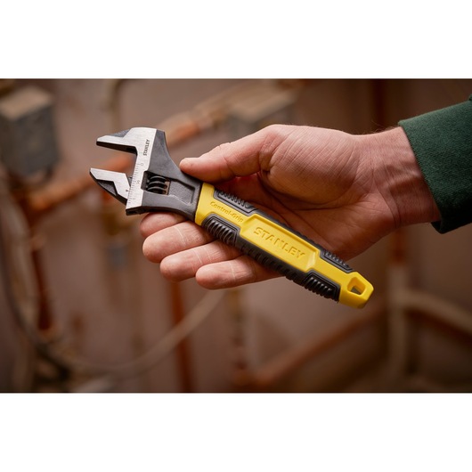 STANLEY 0-90-947 adjustable wrench with yellow and black ControlGrip handle, shown in hand indoors.