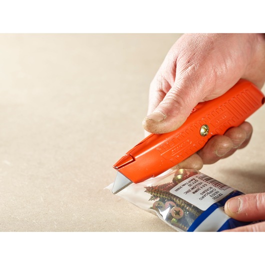 STANLEY 1-10-189 utility knife cutting open a bag of screws, close-up in use.
