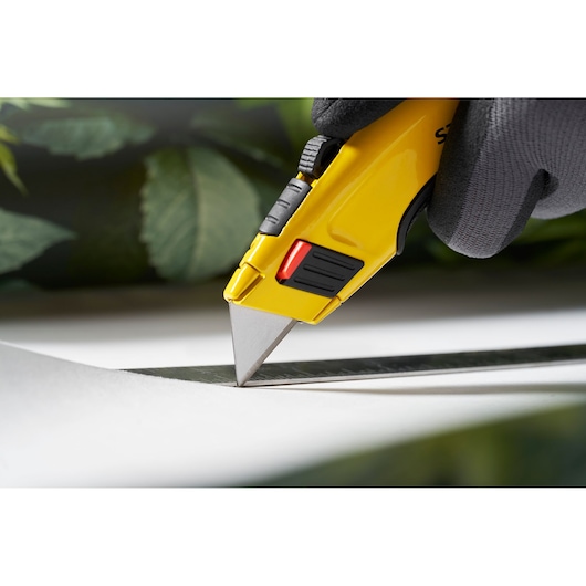Photo of STANLEY 1-11-700 utility knife cutting paper with a straight edge, close-up on blade and handle.