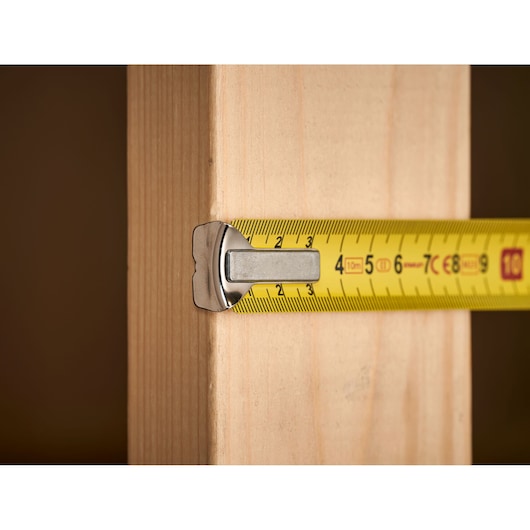 STANLEY 1-33-442 tape measure measuring wooden plank, close-up side view.