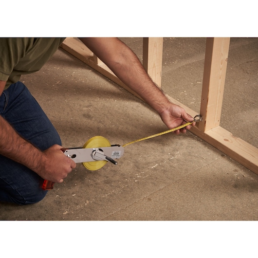 STANLEY 1-34-477 measuring tape reel in use on construction framing, angled side view.