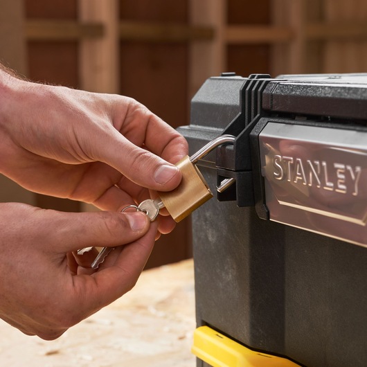 Close-up of STANLEY 1-70-316 toolbox being locked with a brass padlock and keys.