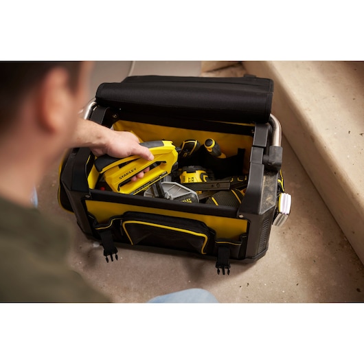 Photo of STANLEY 1-79-213 tool bag with open top, containing yellow and black hand tools on the floor.