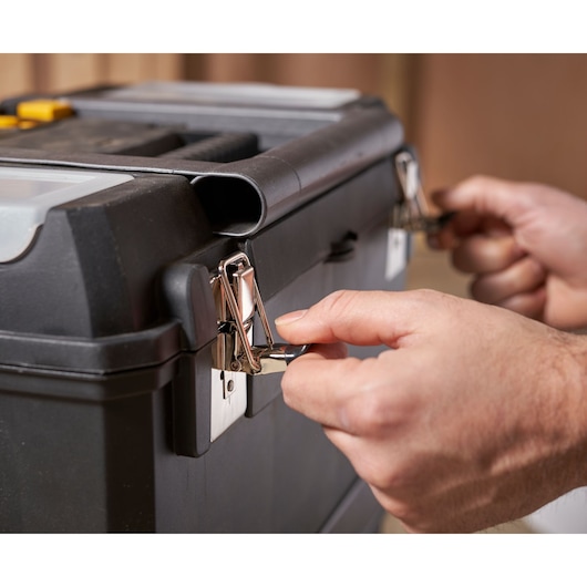 STANLEY 1-93-968 toolbox close-up, hands opening metal latches, front angle.