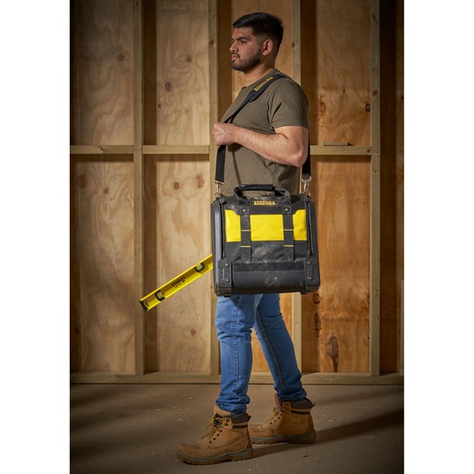 STANLEY 1-94-231 tool bag with yellow and black color, carried with shoulder strap in construction setting.