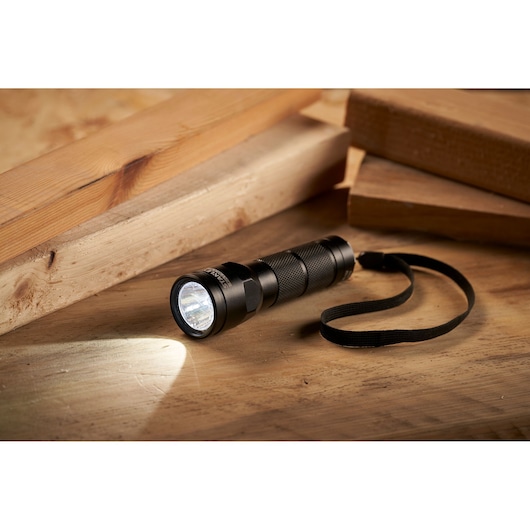 STANLEY 1-95-152 black LED flashlight with wrist strap, shown on a wooden surface with planks.