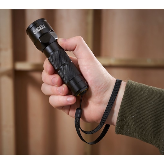 STANLEY 1-95-152 compact black flashlight with wrist strap, photography of product held in hand.