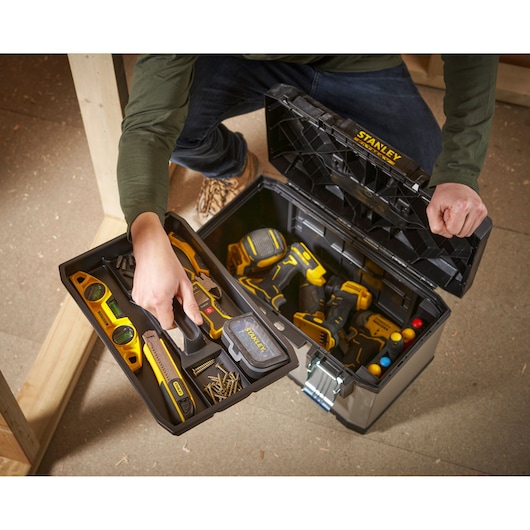 STANLEY 1-95-615 toolbox open with hand holding tray filled with tools and screws on site.