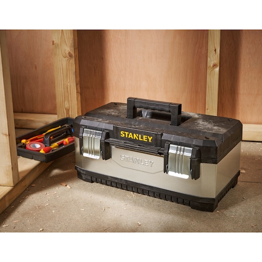 STANLEY 1-95-618 tool box with black lid and metal latches on workshop floor, tray of tools beside it.