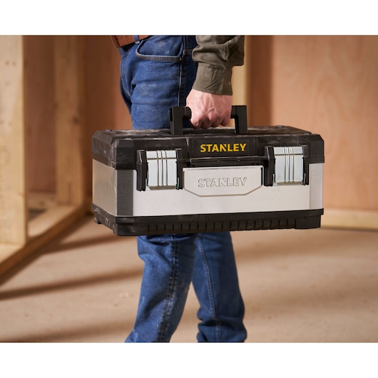 STANLEY 1-95-618 toolbox with metal latches, black and silver, carried by person in jeans.