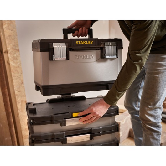 STANLEY 1-95-622 toolbox being placed on stackable storage boxes, shown in use indoors.