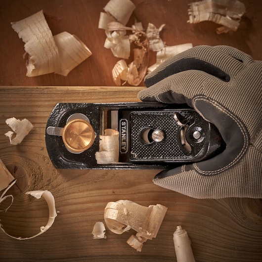 Photo of STANLEY 12-020 hand plane tool in use on wood, surrounded by wood shavings, top view.