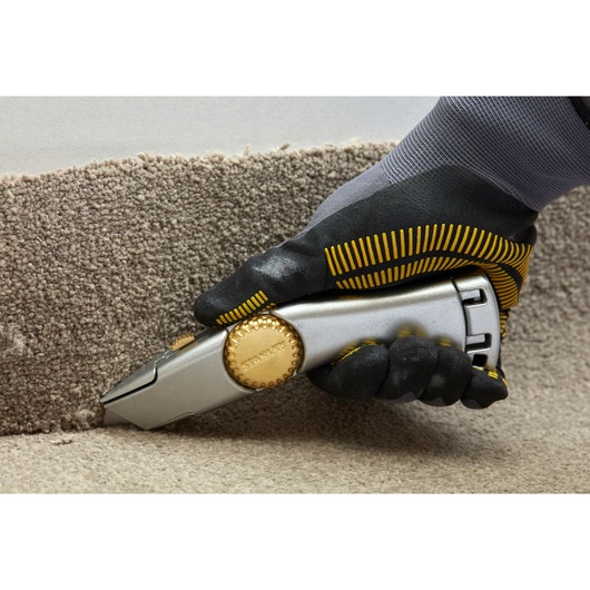 STANLEY 2-10-122 utility knife cutting carpet, close-up photography of hand in work glove.