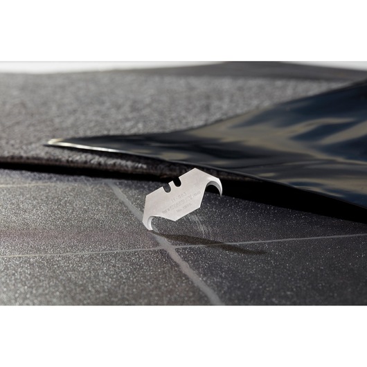 STANLEY 2-11-983 utility blade on a textured black surface, close-up angle, product photography.
