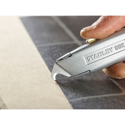 STANLEY 2-11-983 utility knife cutting tile, close-up photography.
