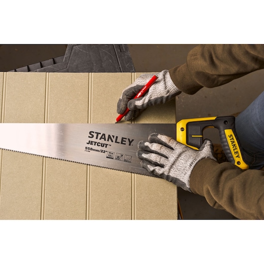 Photo of STANLEY 2-15-244 handsaw with yellow handle and JETCUT blade, used to mark a cut line on wood.