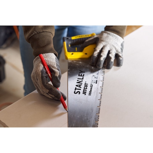 STANLEY 2-20-037 hand saw with yellow and black handle, user wearing gloves marking wood with a red pencil.