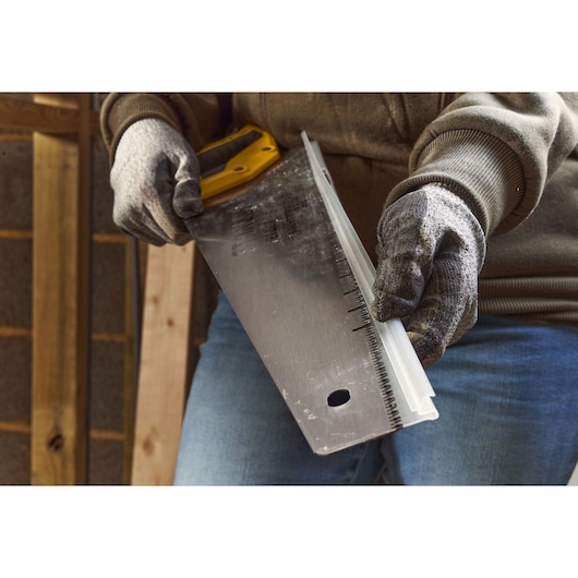 Photo of STANLEY 2-20-037 handsaw with yellow handle, blade guard, held by gloved hands.
