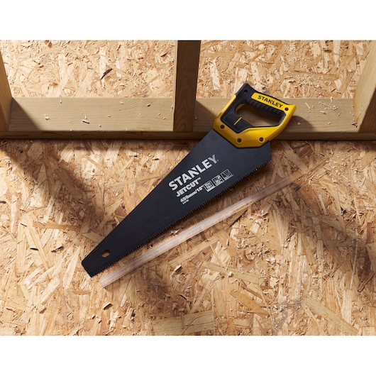 Stanley 2-20-180 hand saw with yellow handle, angled on wooden sheet, construction setting.