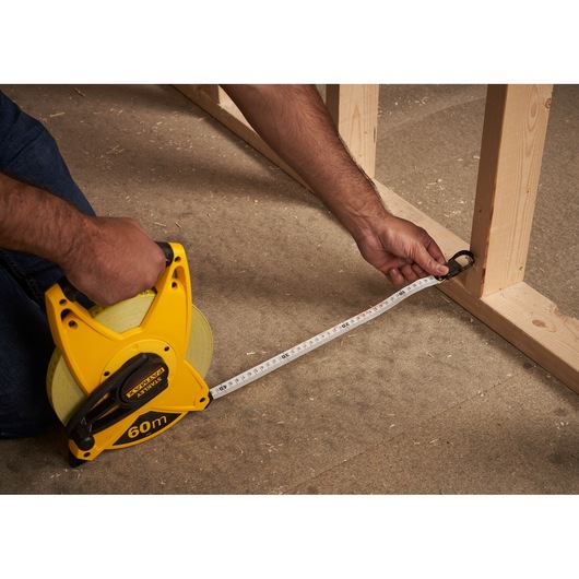 STANLEY 2-34-824 measuring tape reel, 60m, photography of product in use measuring wooden frame.
