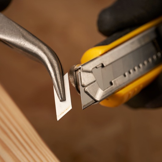STANLEY 3-11-301 utility knife blade being snapped off with pliers, close-up photography.