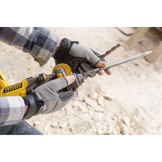 Photo of STANLEY FMCD900B grinder in use outdoors, operator wearing gloves sharpening a metal rod.