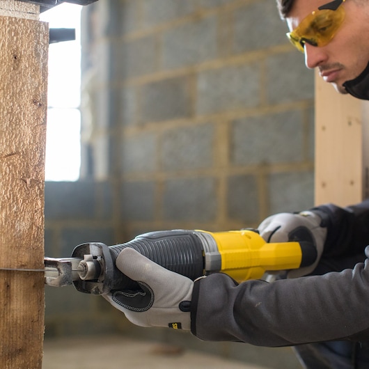 STANLEY FME360 reciprocating saw in use cutting wood, close-up view, user wearing gloves and safety glasses.
