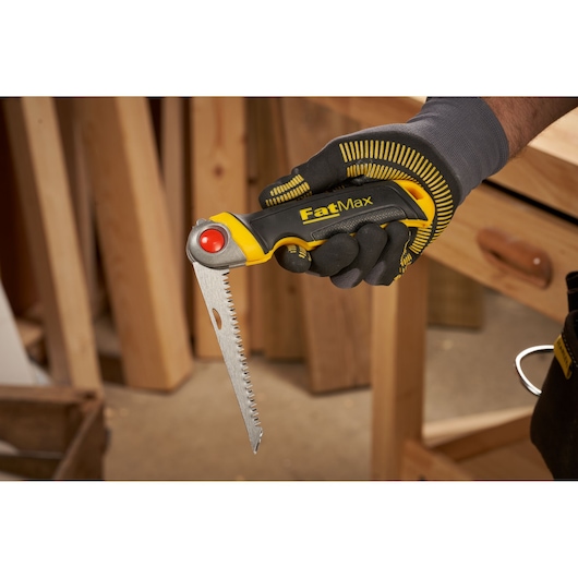 STANLEY FMHT0-20559 FatMax folding saw with yellow and black handle held in gloved hand, angled side view.
