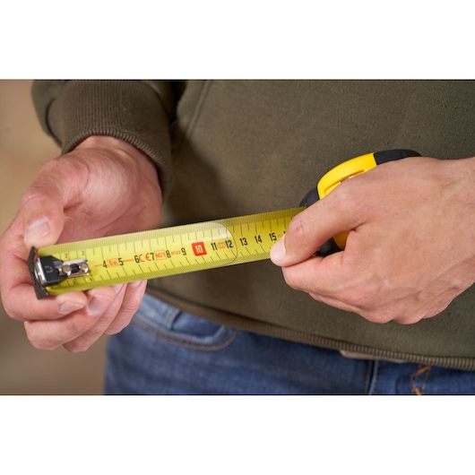 STANLEY FMHT0-33864 tape measure in use, close-up showing yellow tape and clear markings.