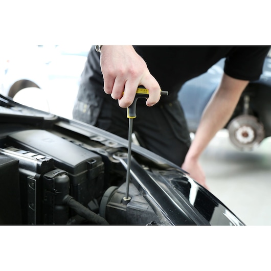 Photo of STANLEY FMHT0-69049 T-handle screwdriver in use on car engine, close-up view.