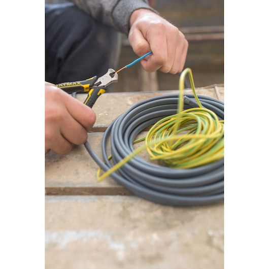 STANLEY FMHT0-80519 pliers cutting wire, close-up photo with coiled electrical cables on workbench.