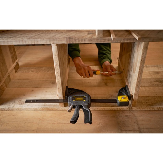 Photo of STANLEY FMHT0-83234 trigger clamp securing wooden boards during assembly, photography from front angle.