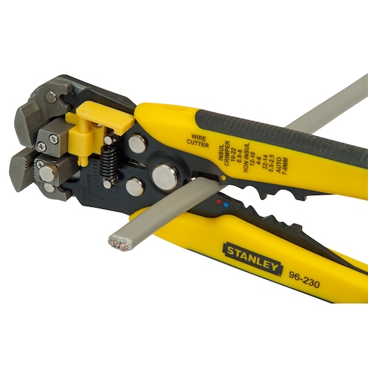 STANLEY FMHT0-96230 wire stripper and cutter tool in use with yellow and black handles, close-up on white background.