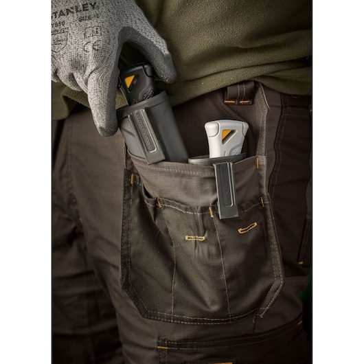 STANLEY FMHT10500-0 utility knives in a worker's pocket, close-up photography with gloves and workwear.