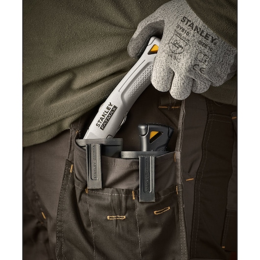 Photo of STANLEY FMHT10501-0 utility knife in work pants pocket, held by gloved hand.