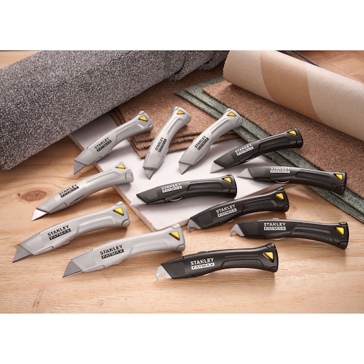 STANLEY FMHT10502-9 utility knives in grey and black with yellow accents, arranged on wooden surface.