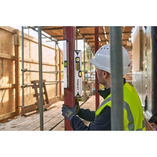 STANLEY FMHT43671-1 spirit level used by a worker in safety gear on a construction site.
