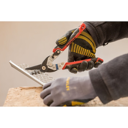 STANLEY FMHT73755 metal shears cutting mesh, close-up photo, worker wearing black and yellow gloves.