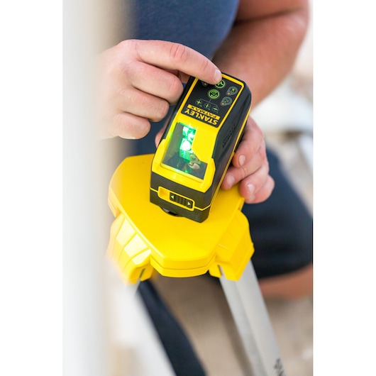 STANLEY FMHT77586-1 laser level on tripod, close-up of hand adjusting controls.