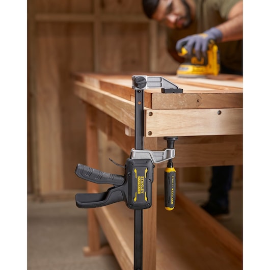 STANLEY FMHT83008-0 heavy-duty bar clamp attached to wooden workbench, side angle photo.