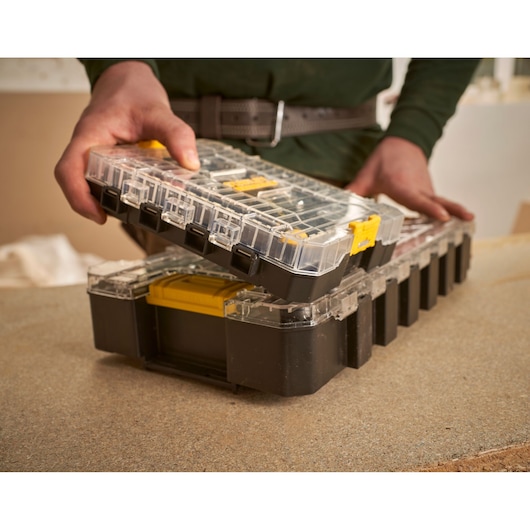 STANLEY FMMT98102-0 black organizer with clear lid and yellow latch, held by hand on workbench.