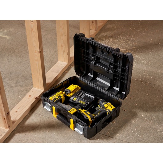 STANLEY FMST1-71966 black tool box with yellow latches, open, showing drill and accessories on workshop floor.