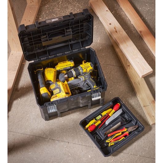 Stanley FMST1-71971 toolbox with assorted power tools and hand tools, overhead angle, workshop setting.