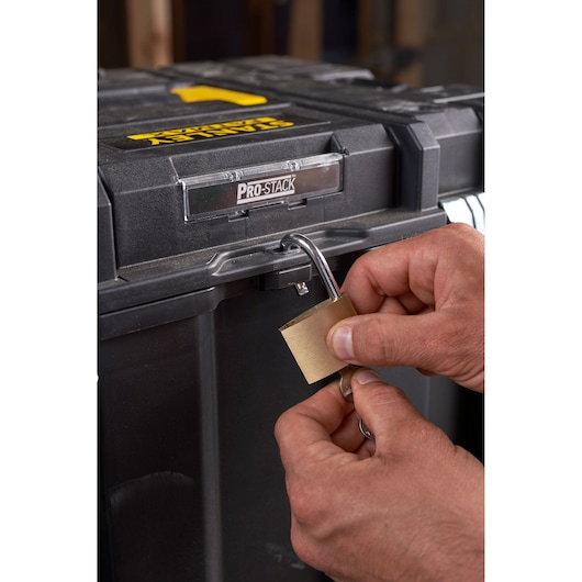 Photo of STANLEY FMST1-75753 toolbox with PRO-STACK label, close-up of hands locking with padlock.